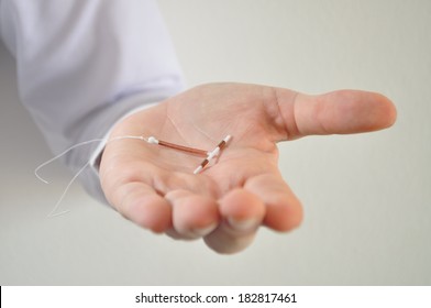 Holding An IUD Birth Control Copper Coil Device In Hand, Used For Contraception - Front View