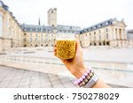Holding a jar with famous dijon mustard on the main square background in Dijon city, France