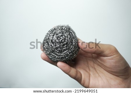 Holding Metal sponge for cleaning and washing dishes on white. Steel wool dishwashing