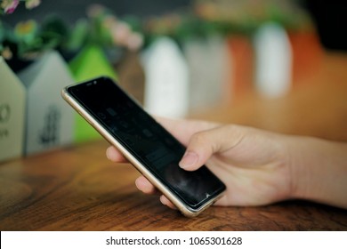 Holding Mobile Phone At Cafe