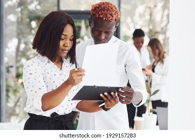 Holding Notepad. Group Of African American Business People Working In Office Together.