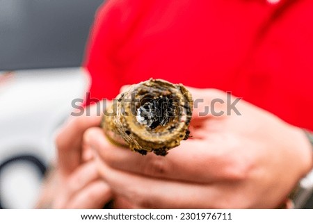 Holding an old corroded galvanized water line. A pice of old water line that has been cut out. Looking in to the center of a corroded pice of water line. 