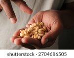 Holding peanuts in a hand while pointing at a snack
