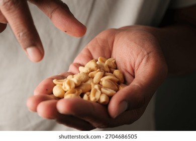 Holding peanuts in a hand while pointing at a snack