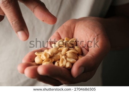 Holding peanuts in a hand while pointing at a snack