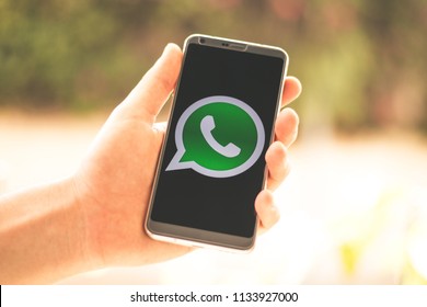 Holding a phone in hand with the WhatsApp app logo shown on screen