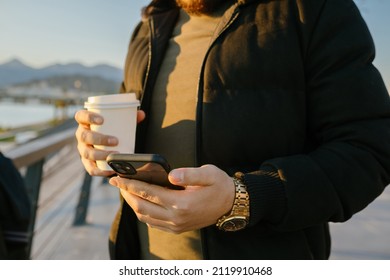 Holding The Phone, Young Man With Watch On His Arm Holding Phone In Other Hand, Close-up Phone, Gold Watch And Smartphone. Selective Focus, Noise Effect.