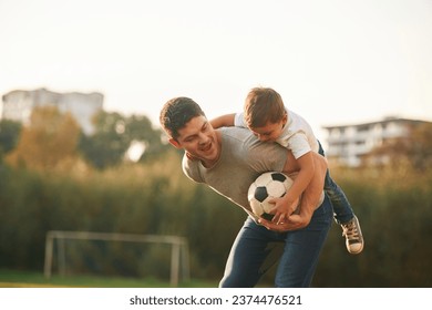 Holding professional soccer ball. Father and little son are playing and having fun outdoors. - Powered by Shutterstock