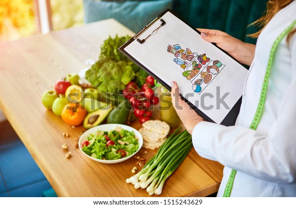 Holding schematic meal plan for diet with various\
healthy products on the background. Weight loss and right nutrition\
concept. Eating food\
pyramid