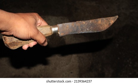 Holding a sharp rusty knife, with a wooden handle, concept of murder using a sharp weapon, stabbing, cutting, slashing, criminality, pointing.