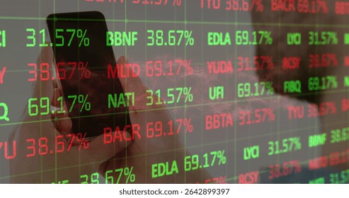 Holding smartphone with left hand in office, displaying stock data on transparent panel, copy space. Technology, finance, stockmarket, data analytics, digital, professional, futuristic