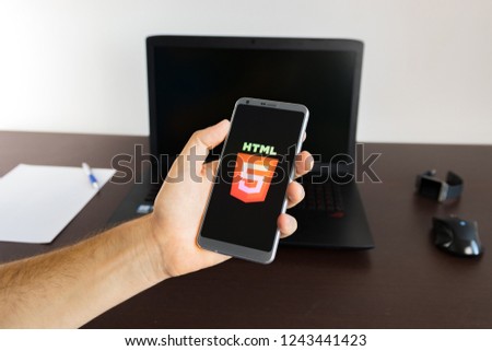 Holding a smartphone on hand with a HTML5 sign logo