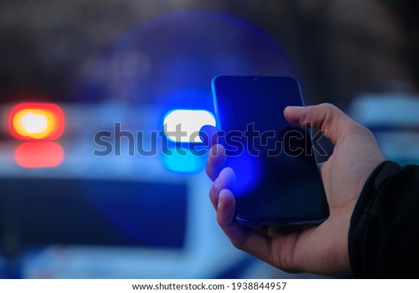 holding smartphone\
and police car\
background\
