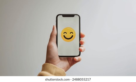 Holding a Smartphone with a Smiley Emoji suitable for business background, posters, wallpapers, banners, greeting cards, and advertising for business entities or brands. - Powered by Shutterstock