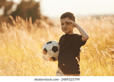 Holding soccer ball. Little boy is having fun outdoors at summertime. - Powered by Shutterstock