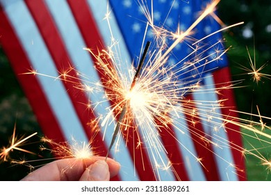 Holding a sparkler in front of an American Flag to celebrate the 4th of July Independence Day