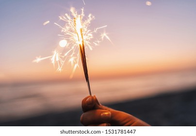 Holding Sparklers At Beach On Sunset