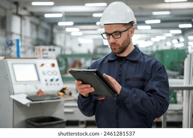 Holding tablet. Factory worker is indoors with hard hat. - Powered by Shutterstock