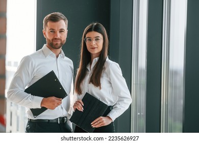 Holding tablet. Man and woman in formal clothes are working together indoors. - Shutterstock ID 2235626927