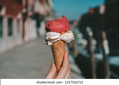 Holding traditional italian ice cream called Gelato in the waffle cone. Venice Murano Island in background