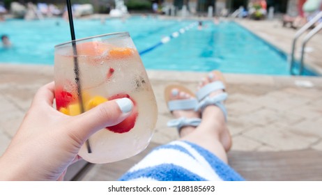 Holding A Tropical Drink By A Swimming Pool At A Resort, Manicured Hands And Pedicured Feet