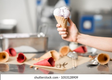 Holding Waffle Cone With Ice Cream At The Kitchen With Food Ingredients And Ice Cream Maker Machine On The Background