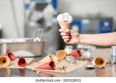 Holding Waffle Cone With Ice Cream At The Kitchen With Food Ingredients And Ice Cream Maker Machine On The Background