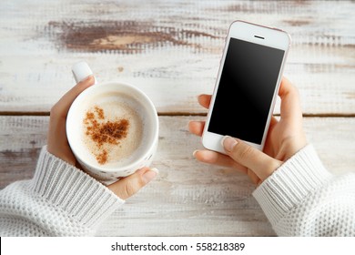 Holding Warm Coffee And Looking At A Phone On A Winter Day. Woman Hands. Top View