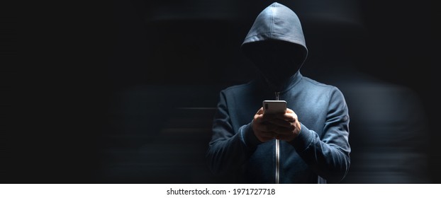 holds the phone on a dark background. hacker concept - Shutterstock ID 1971727718