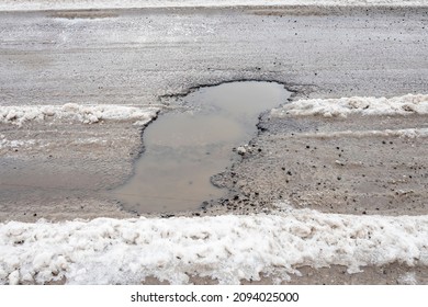 A Hole In The Asphalt After A Rain, A Pothole On The Road After A Spring Thaw.