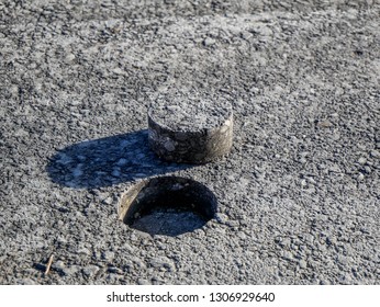 Hole in asphalt pavement, drilled cylindric specimen for laboratory testing.
