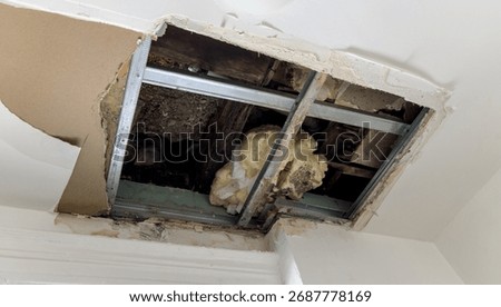 hole in broken ceiling with insulation and old construction sheetrock showing through sheet rock exposed repair water damage bathroom cut out wall repairing damaged