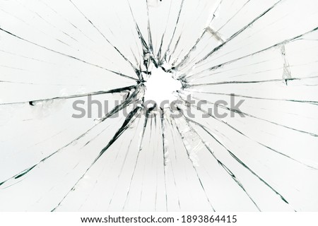 The hole in the broken and cracked glass, closeup 