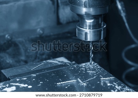 The hole chamfering process on NC milling machine with drill tools in the light blue scene.  The metal working concept on the milling machine.