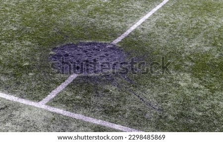A hole in the ground from a cannon shell explosion filled with fresh earth at a football stadium. Shelling crater in the city. Playground. War in Ukraine. Destruction of civilian infrastructure
