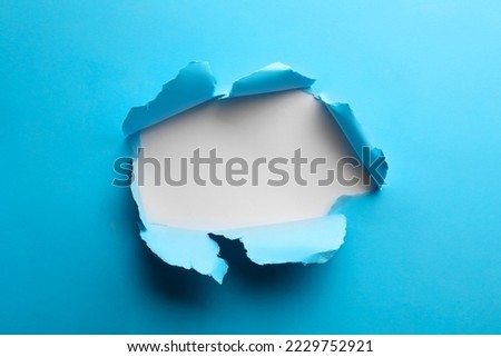 Hole in light blue paper on white background