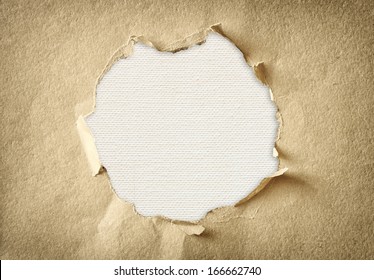hole made of torn paper over textured canvas background 