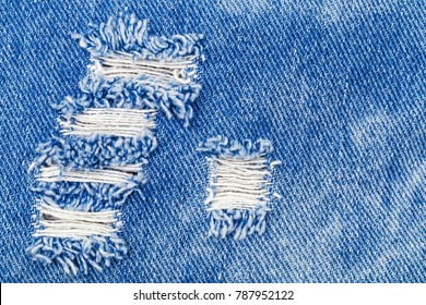 Hole On Denim Jeans. Ripped Destroyed Torn Blue Jeans Background. Close Up Blue Denim  Jean Texture 