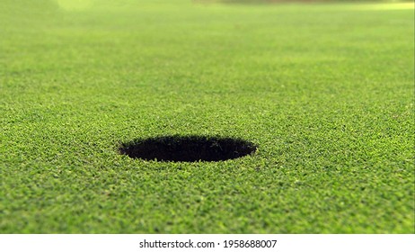 A hole on the golf course in close up view with green grass ground background. - Shutterstock ID 1958688007