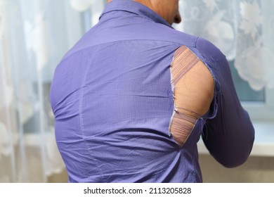 a hole on a purple man's shirt. Strong man rips purple shirt