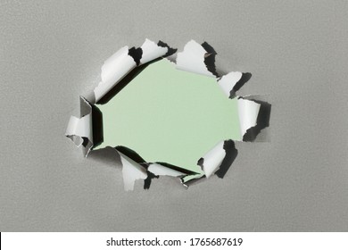 Hole in paper with green background. Ripped torn paper texture