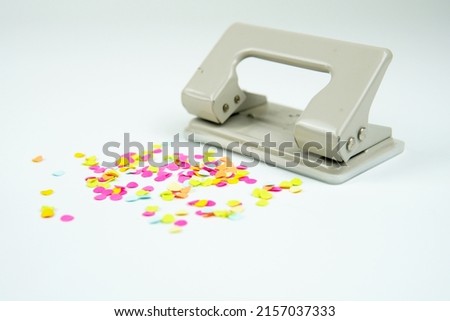        Hole puncher and colorful confetti like punched paper isolated on white                        