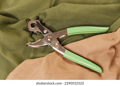 Hole puncher for leather and cardboard on the background of natural fabric, close up, top view. Content for sewing workshops, ateliers for tailoring clothes - Powered by Shutterstock