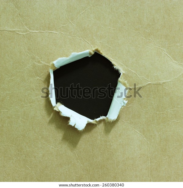 Hole
ripped in paper on black background. Copy
space