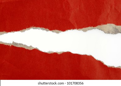 Hole ripped in red paper on plain background