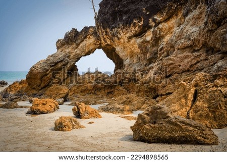 the hole in the rock mountain on the beach with dramatic tone 