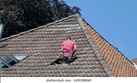 Hole In The Roof Of A Residential Building. Repair Of A Tile Roof After A Storm Damage.