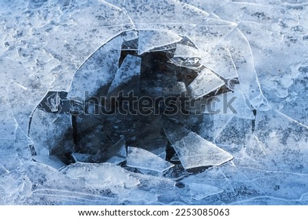 Hole in thin ice on a frozen lake, abstract winter background photo