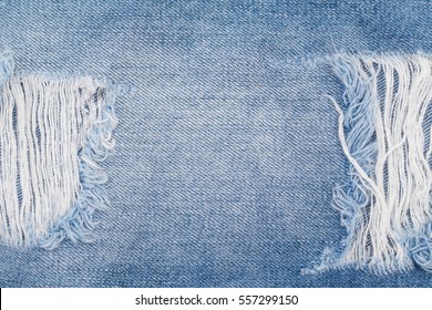 Hole And Threads On Denim Jeans. Ripped Destroyed Torn Blue Jeans Background. Close Up Blue Jean Texture 