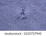 hole in a violet woollen jumper, hole in a purple woollen jumper, texture of a purple crocheted sweater as a background, a fragment of a purple crocheted front surface close up 